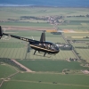 R44 in flight over green fields